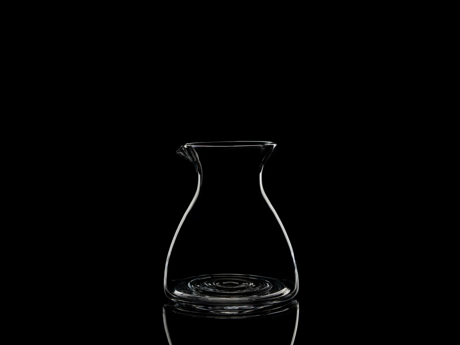 Caraffa in vetro scolpita, disegnata dalla luce su fondo nero
