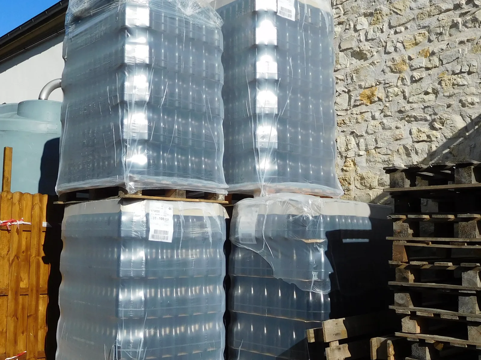 Paletes de garrafas de vidro a granel, dispostas por camadas sobre folhas separadoras e filmadas